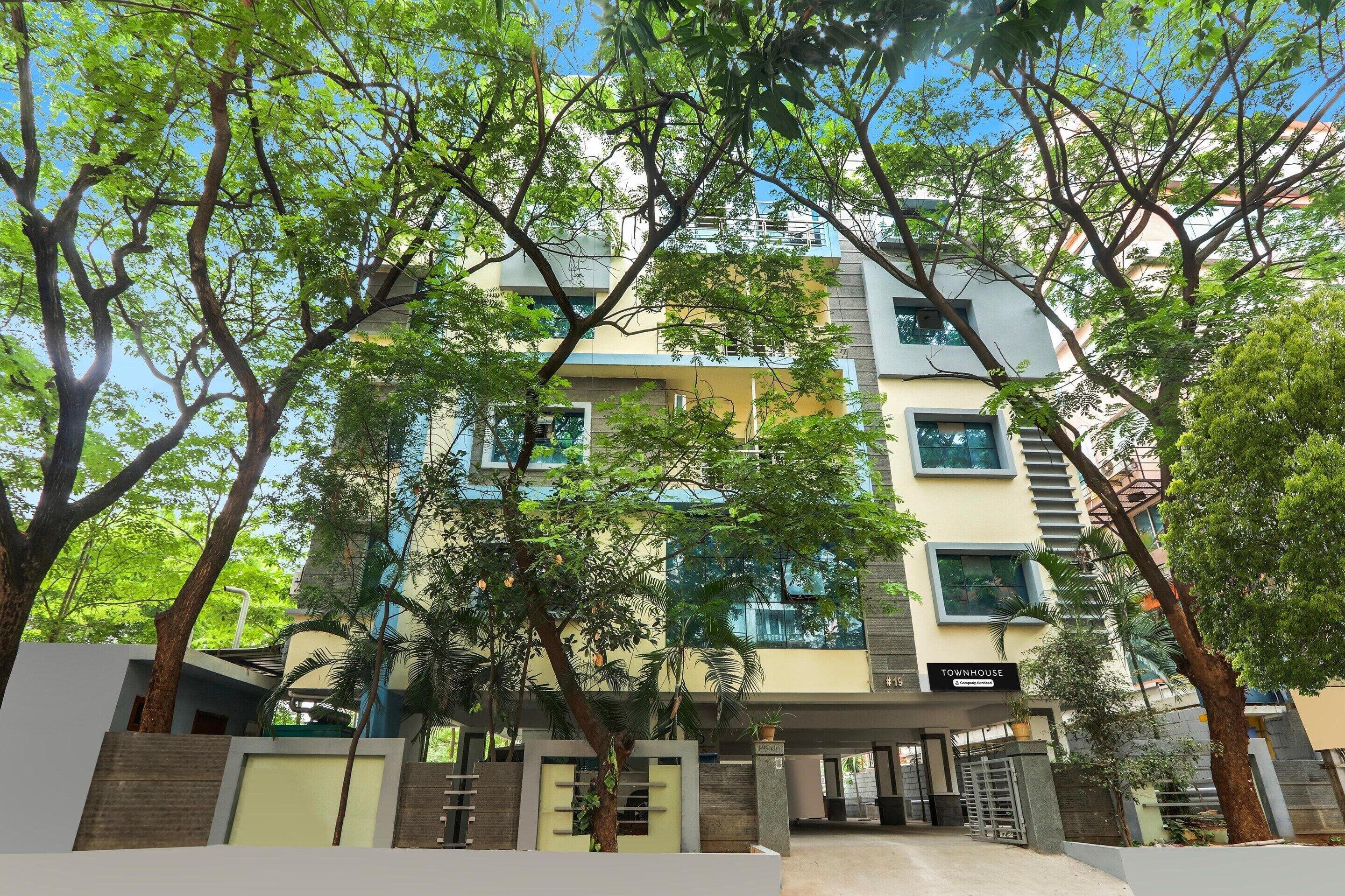 A multi-story building with a covered entrance, surrounded by trees.