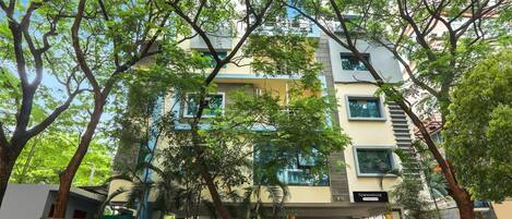 A multi-story building with a covered entrance, surrounded by trees.