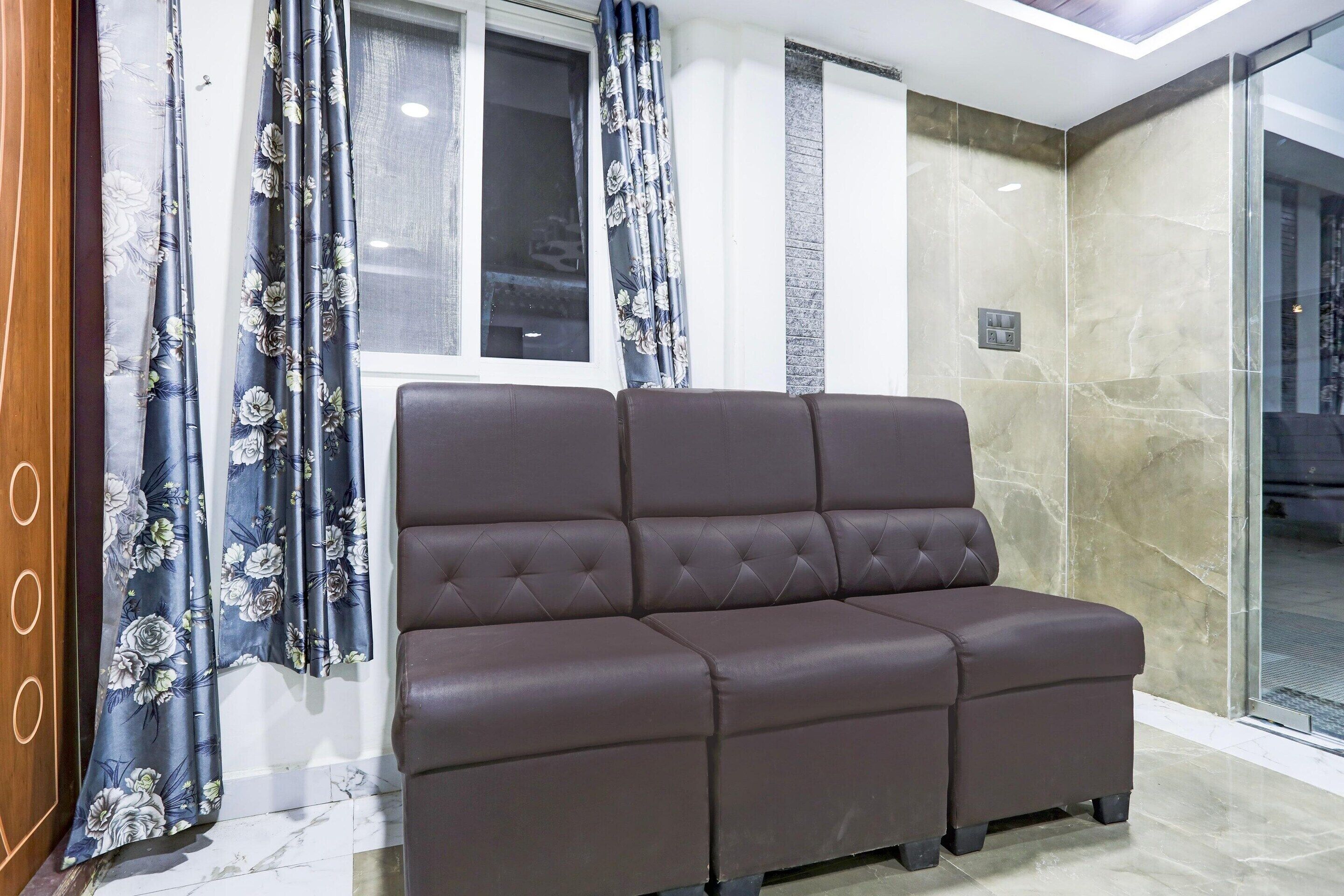 A brown leather sofa in a modern room with a glass partition and a window with curtains.