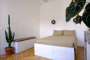 Ein Schlafzimmer mit Bett, einer Bank, einer Topfpflanze und Wanddekoration.
