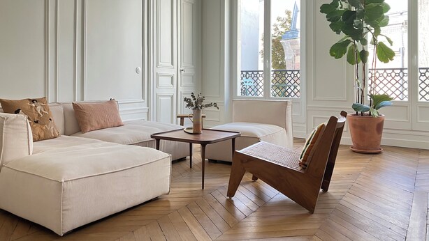 Una habitación con sofá, una silla, una mesita y una planta en maceta.