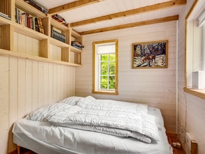 A bedroom with a bed, wooden bookshelves, a window with a view of greenery, and a painting on the wall. - "Heda" - 1.6km to the fjord by Interhome (Hadsund)