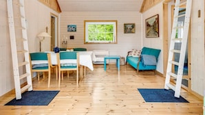 A cozy cabin interior with a wooden floor, a dining table, a sofa, and a window with a view of greenery. - "Heda" - 1.6km to the fjord by Interhome (Hadsund)