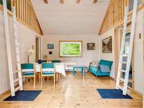 Interior acogedor de una cabaña con una mesa de comedor, sillas, un sofá y una ventana.