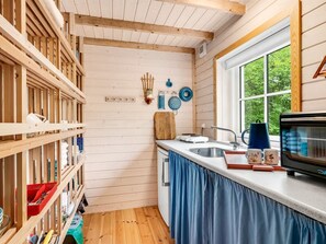 Una cocina compacta con paredes de madera, una ventana y un microondas empotrado.