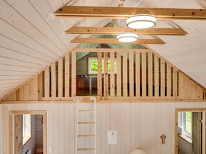 Un interior de madera con techo inclinado, una escalera y un ventanal.