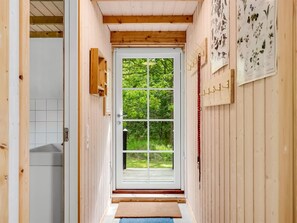 En smal hall med en trädörr som leder ut till ett grönområde.