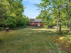 A red cabin with a metal roof, surrounded by trees and grass. - "Heda" - 1.6km to the fjord by Interhome (Hadsund)