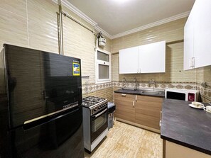 A kitchen with a black refrigerator, a stove, a microwave, and a sink. - 2 bedrooms apartment in rehab city (New Cairo)