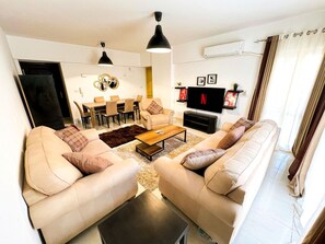 A modern living room with a sofa set, a coffee table, a TV, and a dining area with chairs and a table. - 2 bedrooms apartment in rehab city (New Cairo)