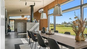 A modern dining area with a long table, black chairs, and a view of the outdoors. - "Safir" - 200m to the fjord by Interhome (Vinderup)