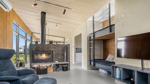 A modern living room with a fireplace, a sofa, a TV, and a bunk bed. - "Safir" - 200m to the fjord by Interhome (Vinderup)