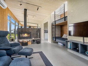Ein modernes Wohnzimmer mit Kamin, Sofa, Fernseher und Etagenbett.