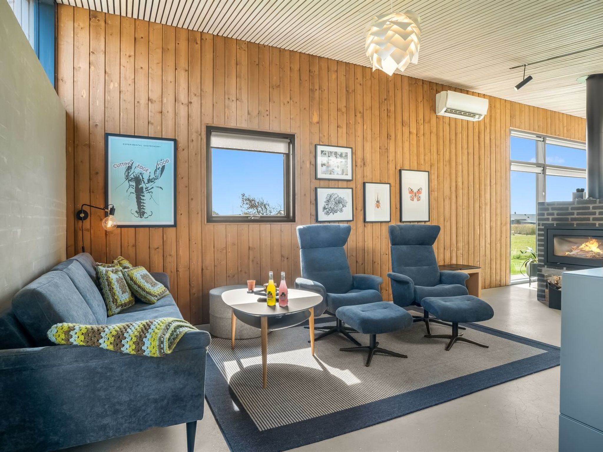 Un salon moderne doté d’une cheminée, de murs en bois et d’œuvres d’art encadrées.
