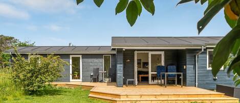 Una casa moderna con un patio, zona de comedor y una puerta visible.