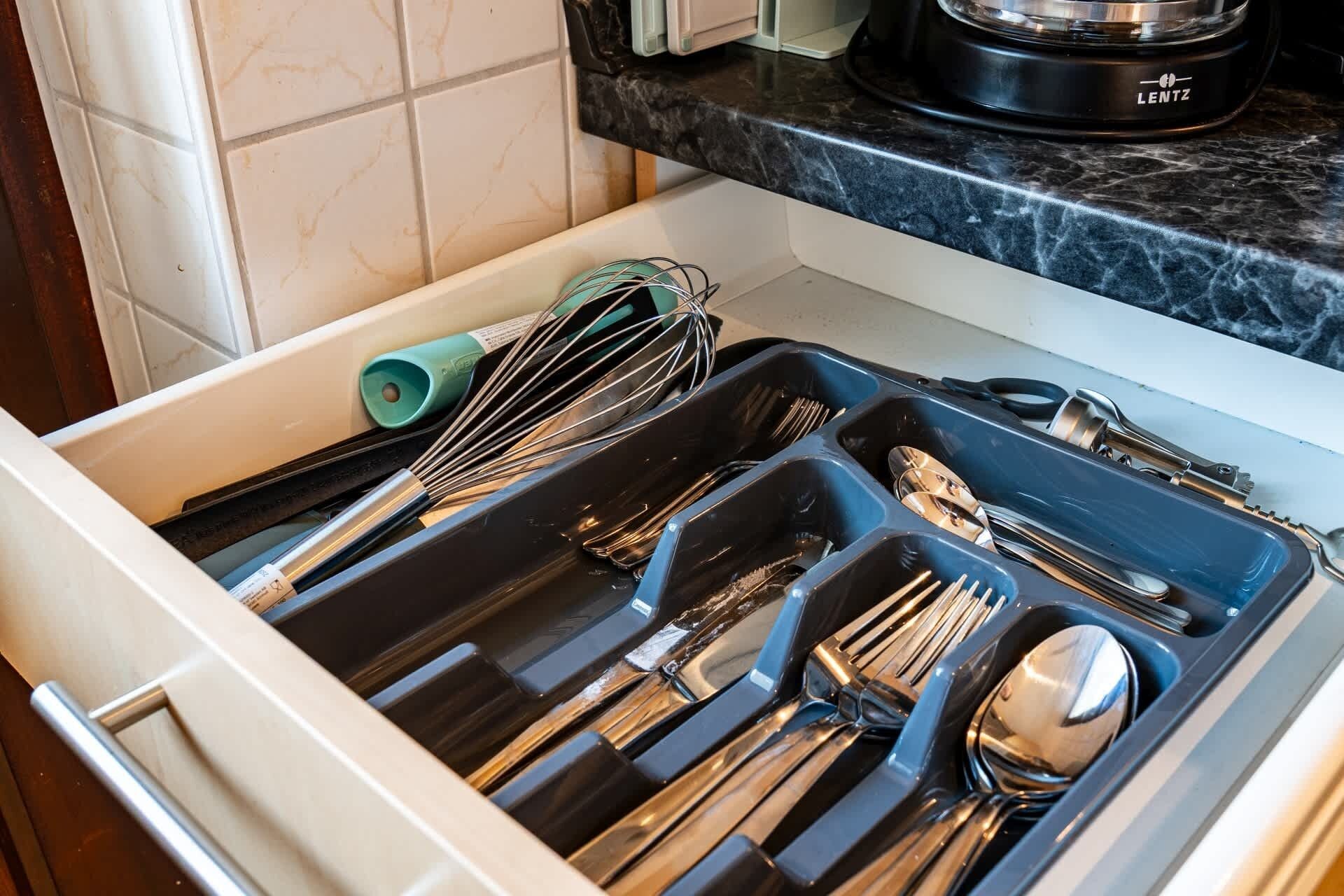 Un cajón de cocina con utensilios y una cafetera LENTZ sobre la encimera.