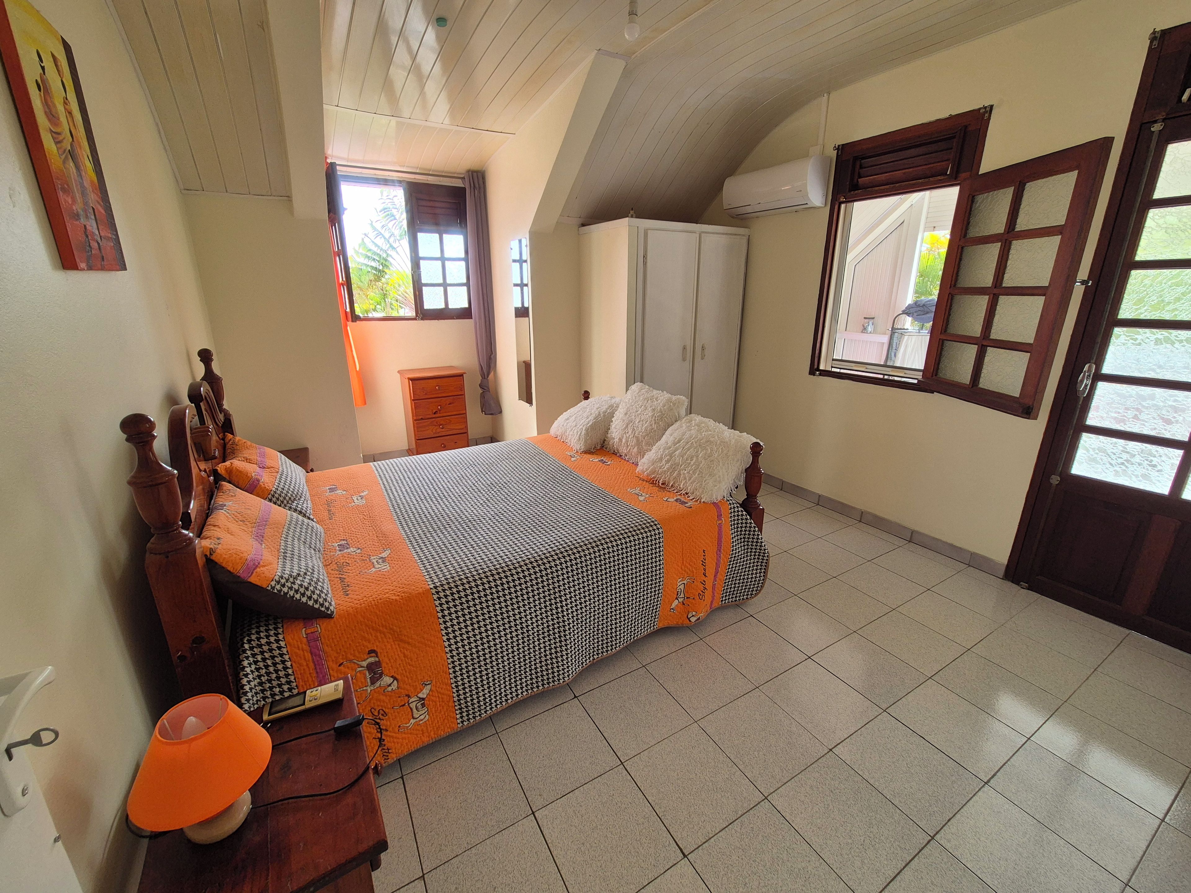 A bedroom with a bed, a dresser, a lamp, and a wardrobe.