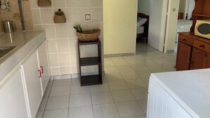 A kitchen with a sink, a small shelf with baskets, and a microwave on a wooden cabinet. - Sainte-Anne | Pointe Marin beach 400m away! (Sainte-Anne)