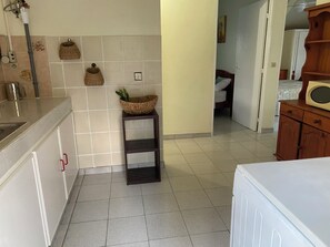 A kitchen with a sink, a small shelf with baskets, and a microwave on a wooden cabinet. - Sainte-Anne | Pointe Marin beach 400m away! (Sainte-Anne)