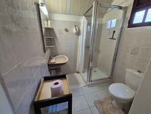 Casa de banho com cabine de duche em vidro, lavatório e sanita.