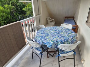 Ein Balkon mit einem runden Tisch, vier Stühlen und einem kleinen Bett.
