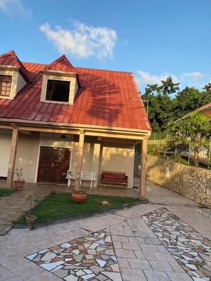 A house with a red roof, a front porch with a bench, and a tiled walkway. - Sainte-Anne | Pointe Marin beach 400m away! (Sainte-Anne)