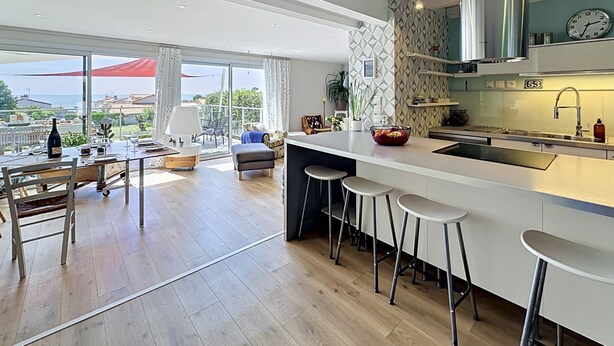 A modern kitchen with a large island, bar stools, and a view of the sea. - L'Incroyable Océane by Interhome (Pornic)