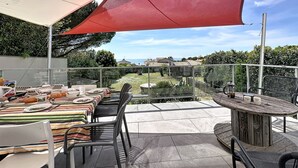 Un patio al aire libre con una mesa lista para comer, sillas y una mesa redonda con una bebida.