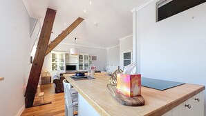 Een moderne keuken met een houten kookeiland, witte kasten en een eethoek met een tafel en stoelen.