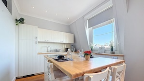 Een moderne keuken met witte kastjes, een houten eiland en een raam met uitzicht.