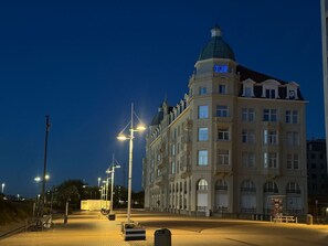Een groot, historisch gebouw met een opvallende koepel en veel ramen, gelegen in een goed verlicht stedelijk gebied in de nacht.