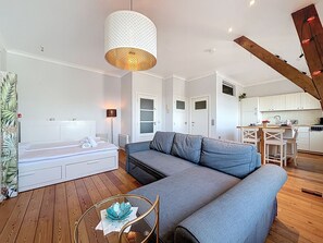 Una sala de estar moderna con un sofá seccional, una mesa de centro de vidrio y una lámpara colgante.