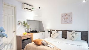 A hotel room with a bed, bedside table, desk, and a wall-mounted air conditioner. - Serenity Hotel Near Tan Son Nhat Airport (Ho Chi Minh City)