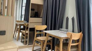 A modern room with a ceiling fan, a table with chairs, and a large window with curtains. - Serenity Hotel Near Tan Son Nhat Airport (Ho Chi Minh City)