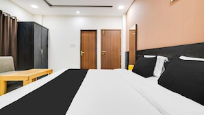 Une chambre d’hôtel avec un lit, un banc en bois, une armoire et deux portes.