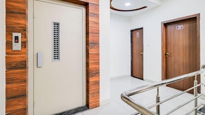 Un couloir d’hôtel avec un mur d’accent en bois, une porte dotée d’une serrure numérique et une main courante en métal.