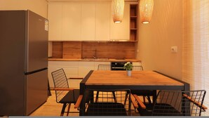 A modern kitchen with a wooden dining table, chairs, and a refrigerator. - SanPietro Vacation Apartment 012 (Plazhi San Pietro)