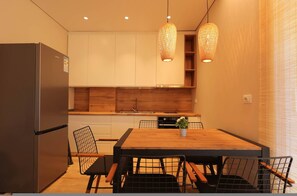 A modern kitchen with a wooden dining table, chairs, and a refrigerator. - SanPietro Vacation Apartment 012 (Plazhi San Pietro)