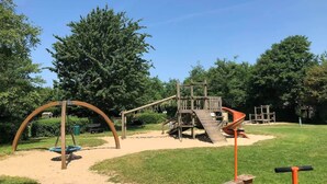 A playground with a swing set, slide, and climbing structures. - Vacation home near the North Sea and forest. Bergen, NH, Schoorl, Schoorldam (Warmenhuizen)