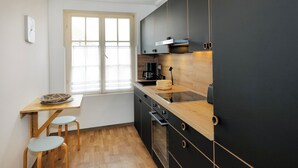 Una cucina compatta con una finestra, un tavolo di legno, due sgabelli e mobili moderni.