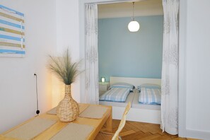 A room with a bed, a table with a vase, and a chair. - Haus Spiegel - Blue Heaven vacation apartment (Lindau (Bodensee))