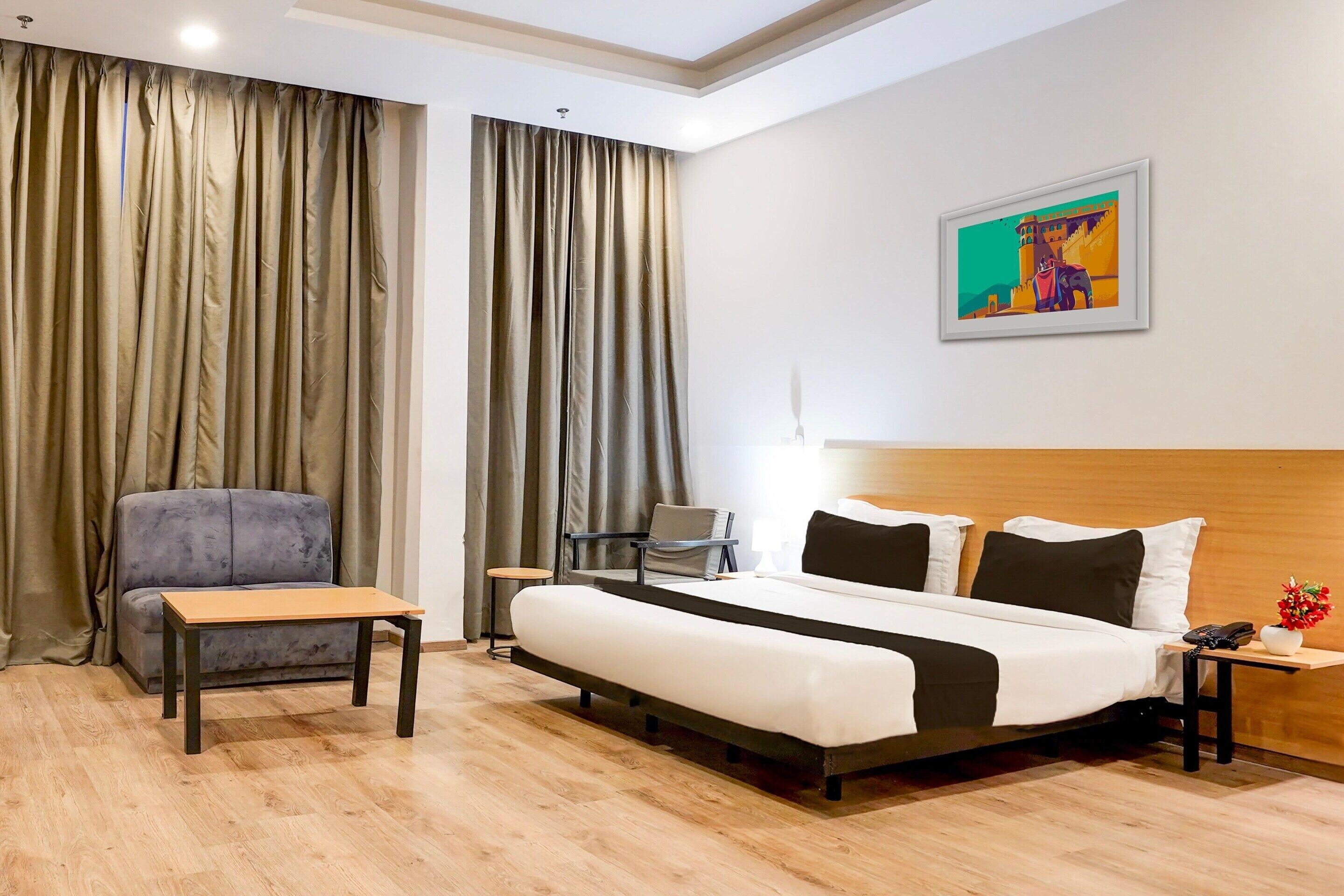 Una camera d'albergo con un letto, una scrivania, una sedia, un divano e un quadro appeso al muro.