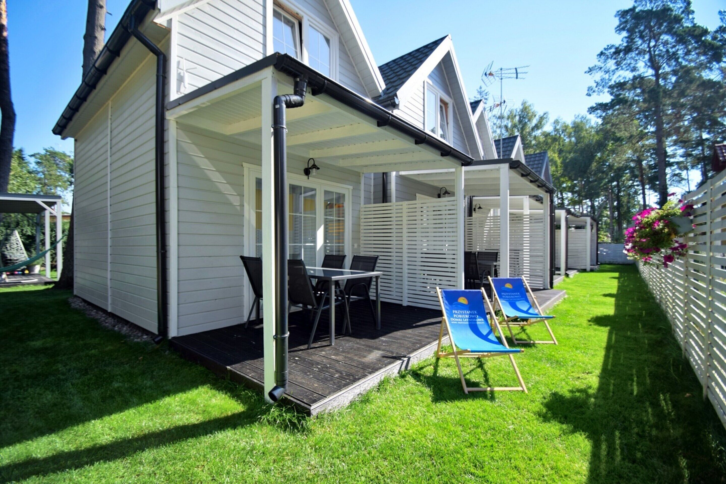 A covered outdoor area with a table and chairs, a sign, and a grassy lawn.