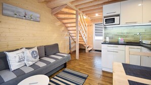 Ein Holzinnenraum mit einer Couch, einer Küche und einer Treppe.
