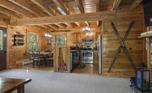 L’intérieur d’un chalet en bois comprend une cuisine, un coin repas et un porte-skis.