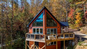Une cabane dotée d’un balcon, entourée du feuillage automnal.