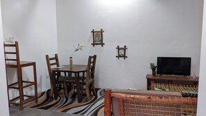 Una sala de estar con televisor, muebles de madera, un tapete estampado y adornos en las paredes.