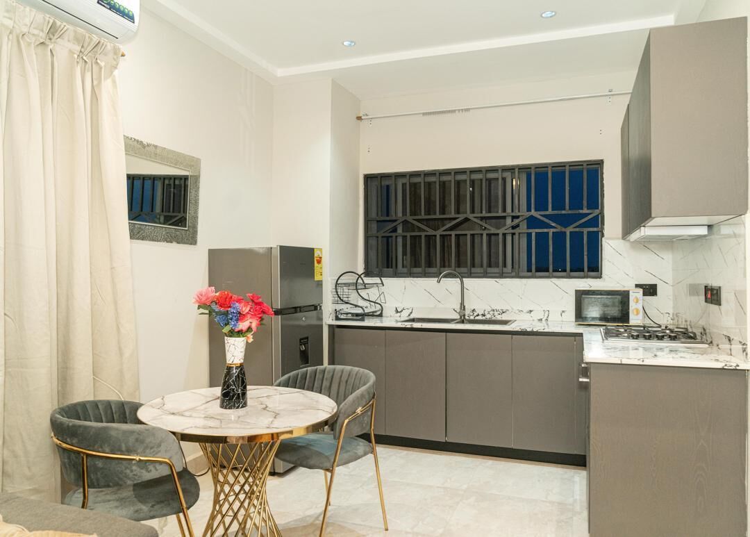 A compact kitchen with a dining area, a refrigerator, a microwave, and a gas stove.