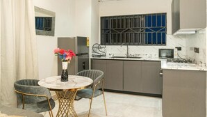 Une cuisine compacte comprenant un coin repas, un réfrigérateur, un four à micro-ondes et une cuisinière à gaz.