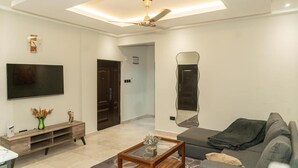 Un salon moderne avec un téléviseur à écran plat, une table basse en bois, un canapé et un ventilateur de plafond.